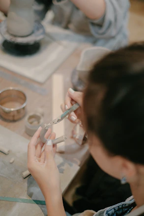 Artisan hands shaping clay in a modern studio with natural light.
