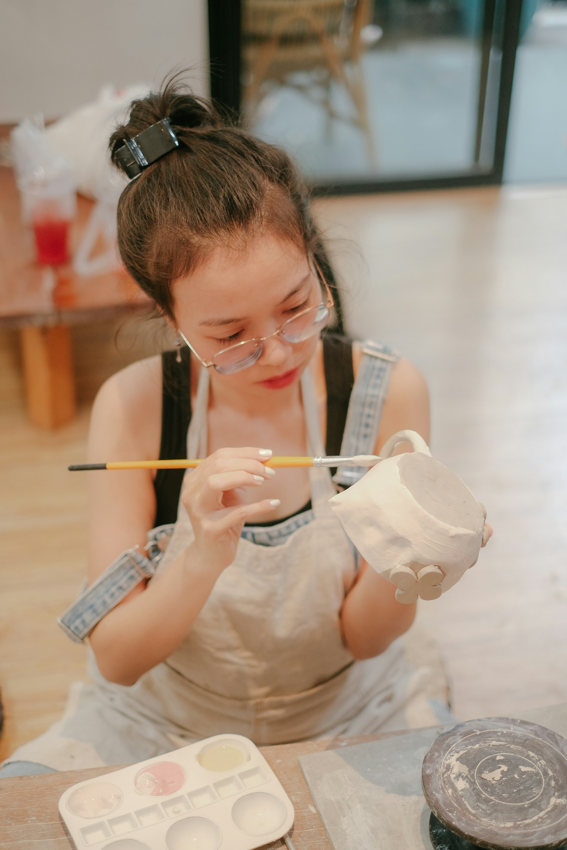 a woman sitting on the floor painting with a brush