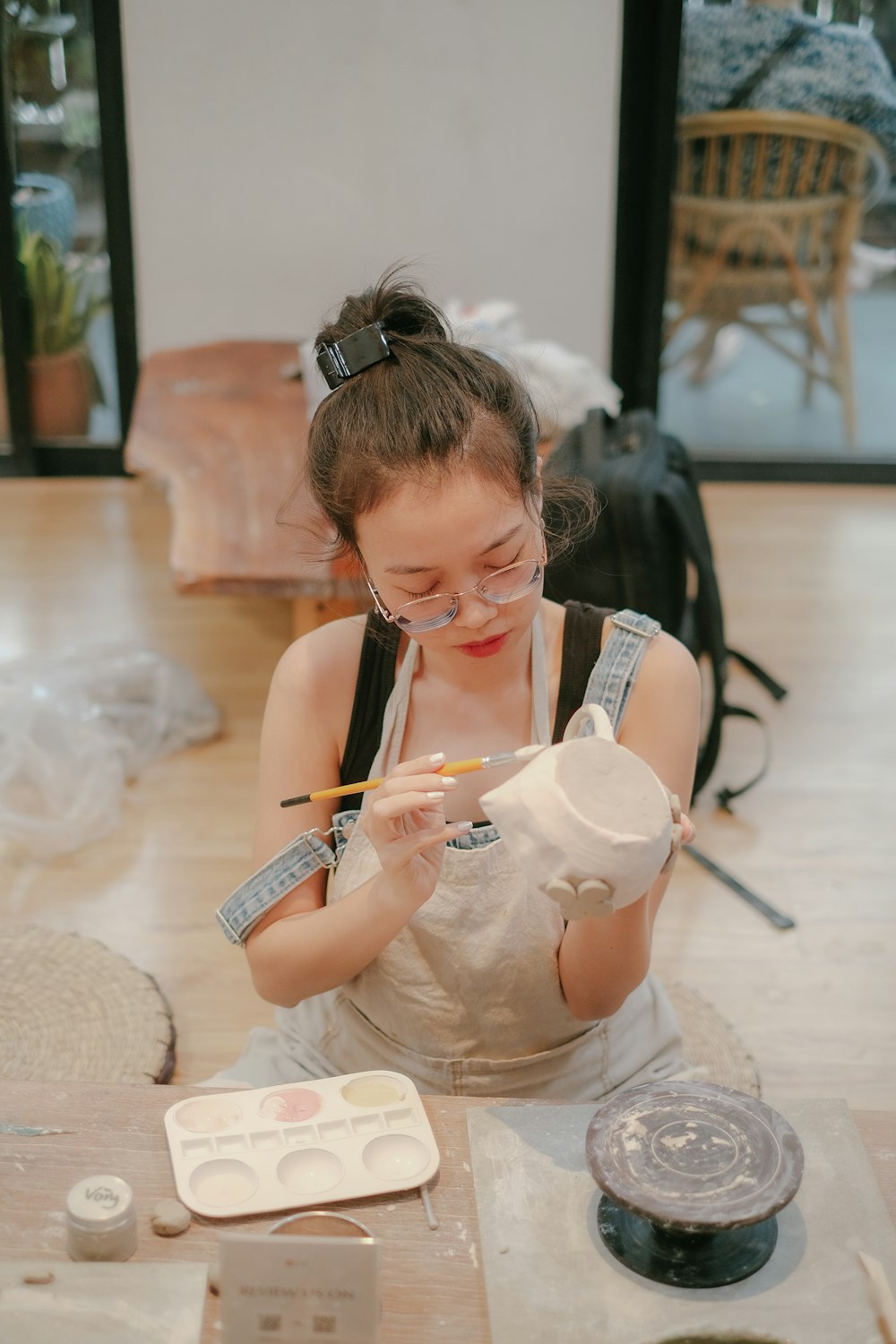 a woman in an apron is painting a vase