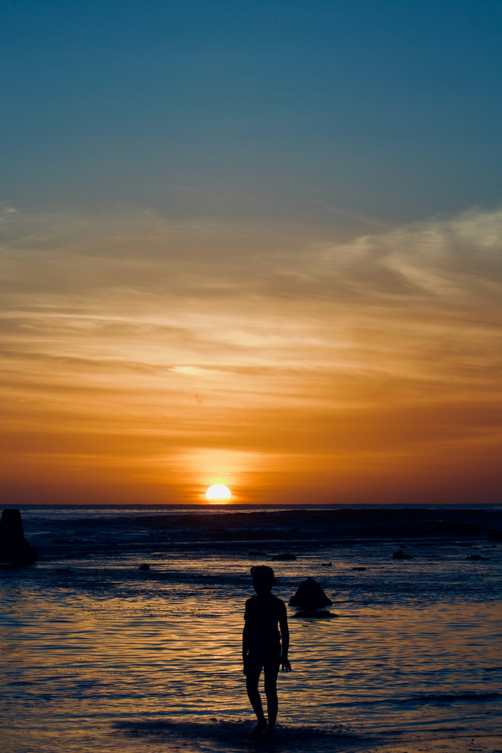 a person standing in the water at sunset