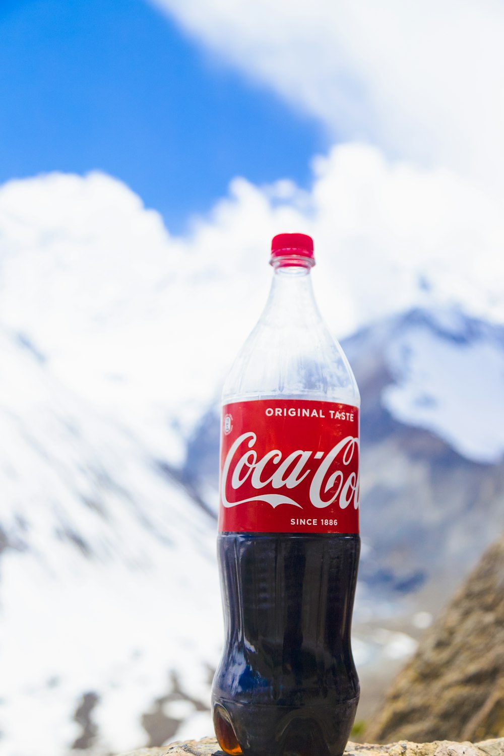 a bottle of coca cola sitting on top of a rock