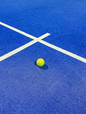a yellow tennis ball on a blue tennis court