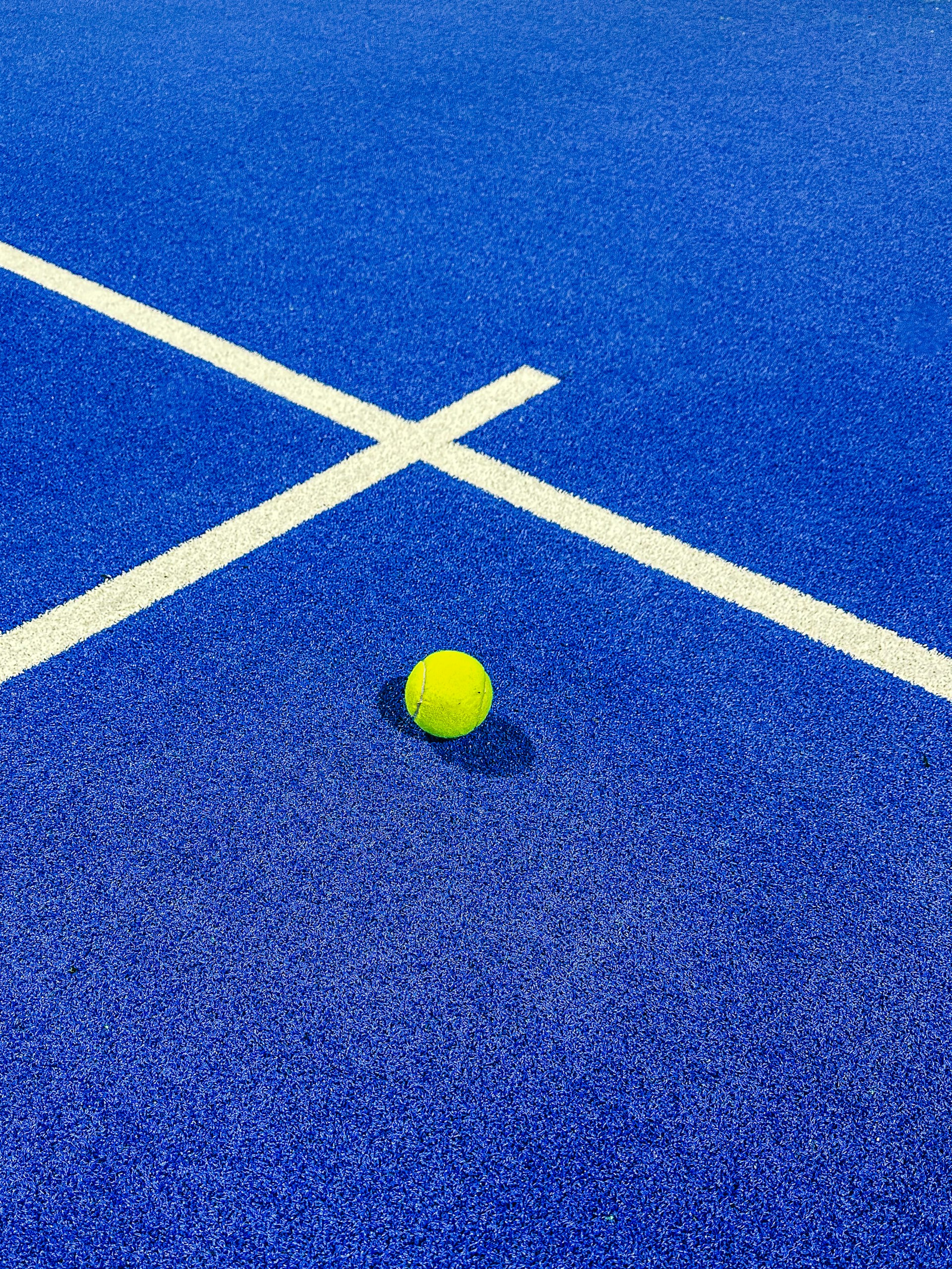 a yellow tennis ball on a blue tennis court