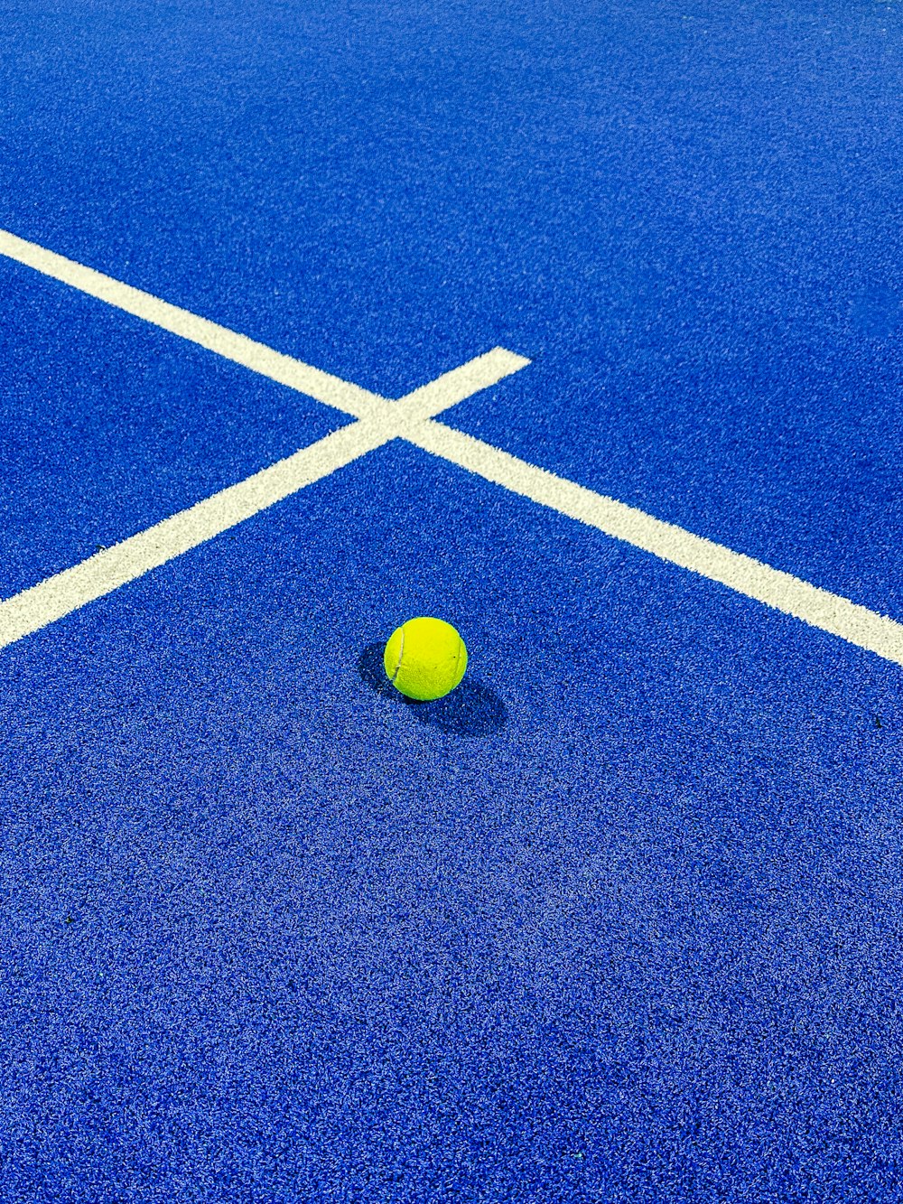 a yellow tennis ball on a blue tennis court