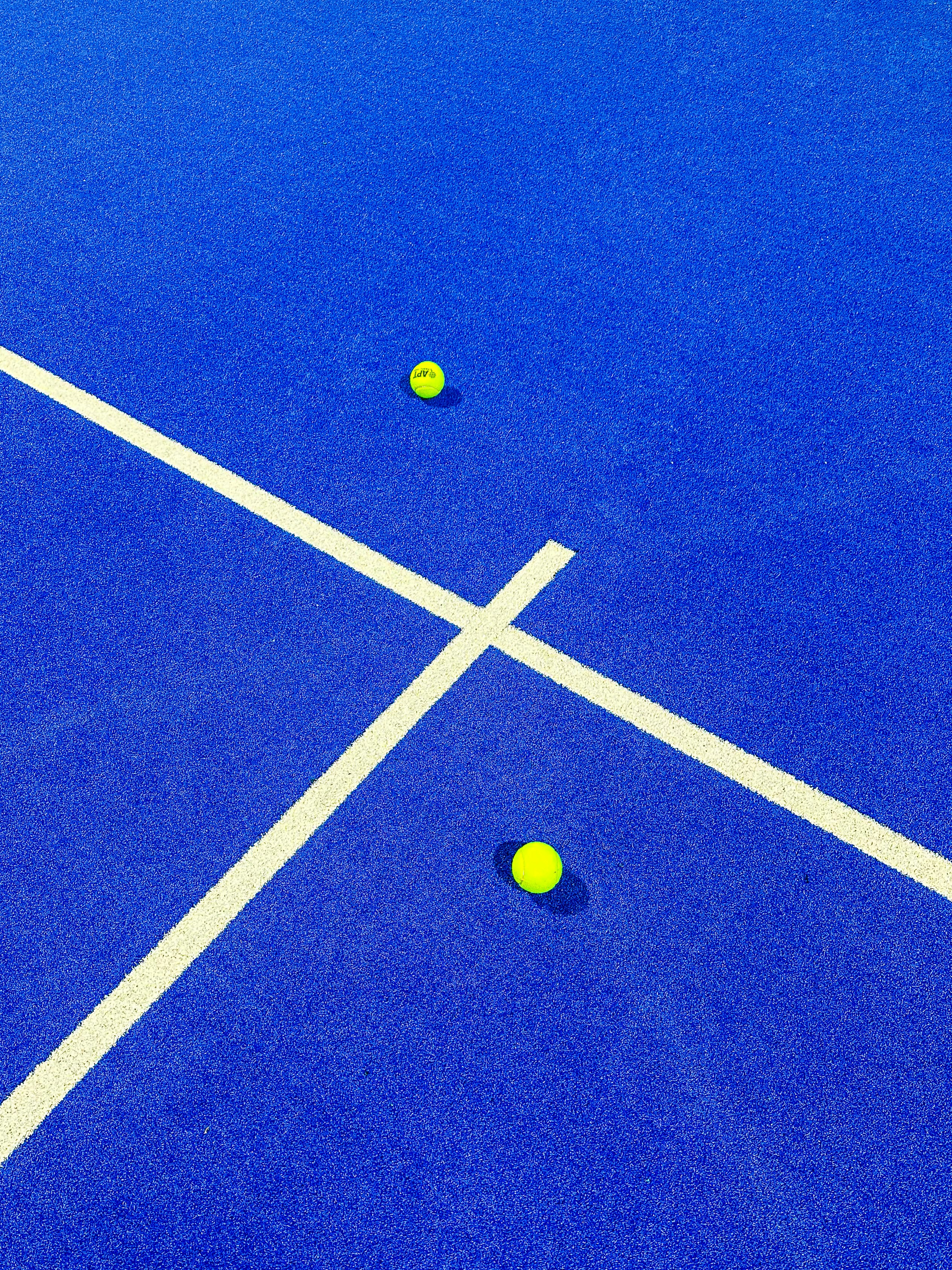 two tennis balls on a blue tennis court