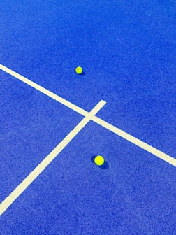 two tennis balls on a blue tennis court