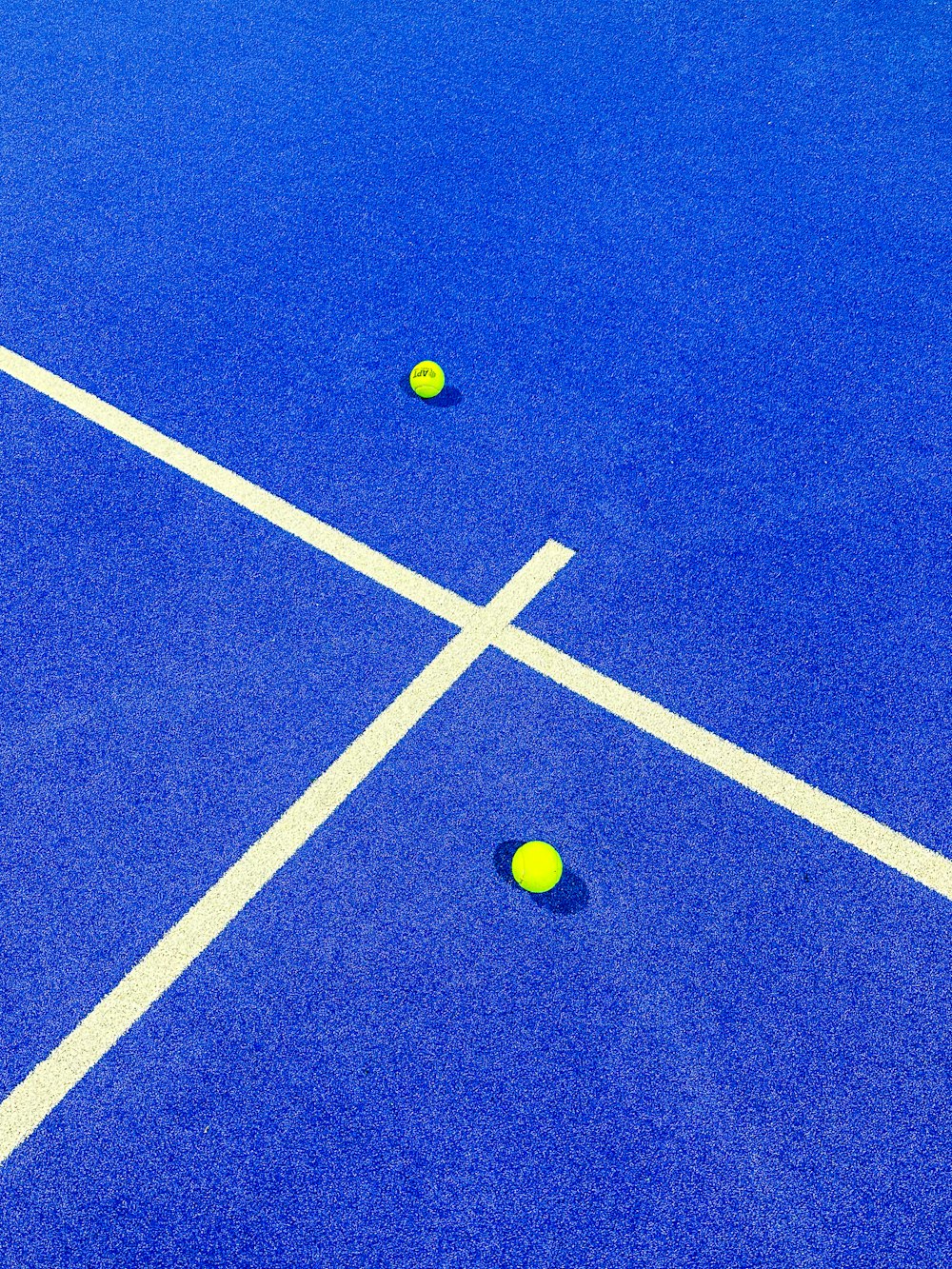 two tennis balls on a blue tennis court