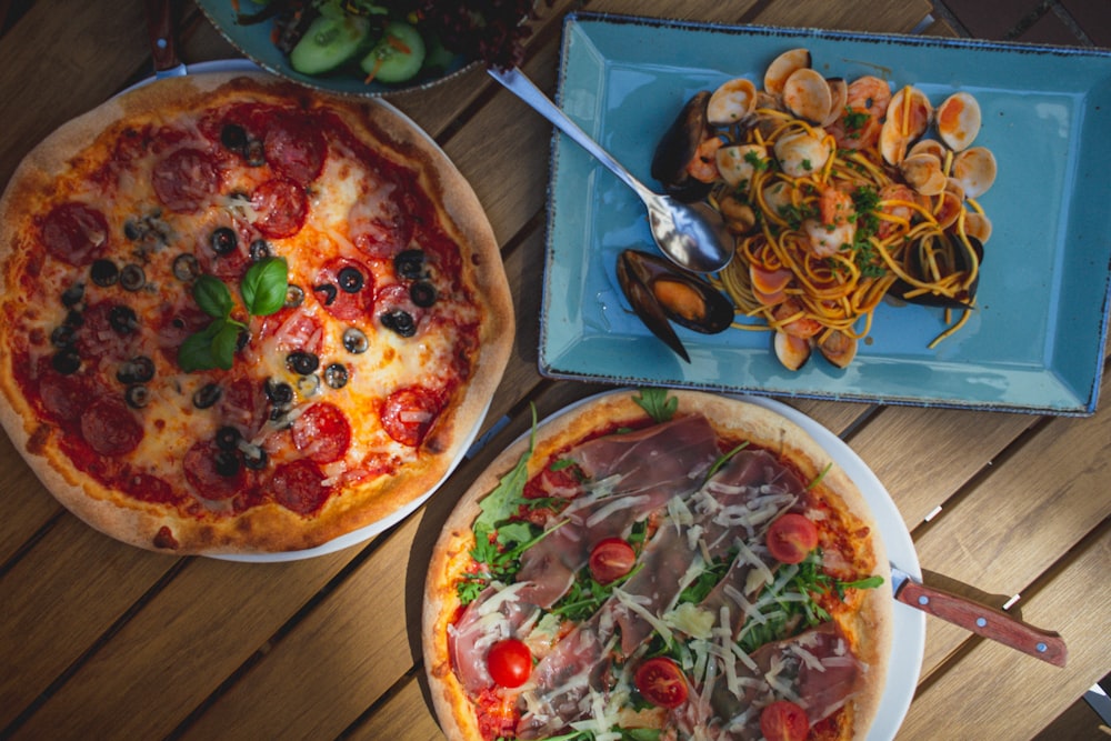 a table topped with two pizzas covered in toppings