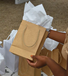 a woman is holding a brown paper bag