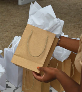 a woman is holding a brown paper bag