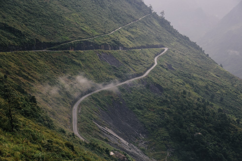 a winding road in the middle of a lush green hillside