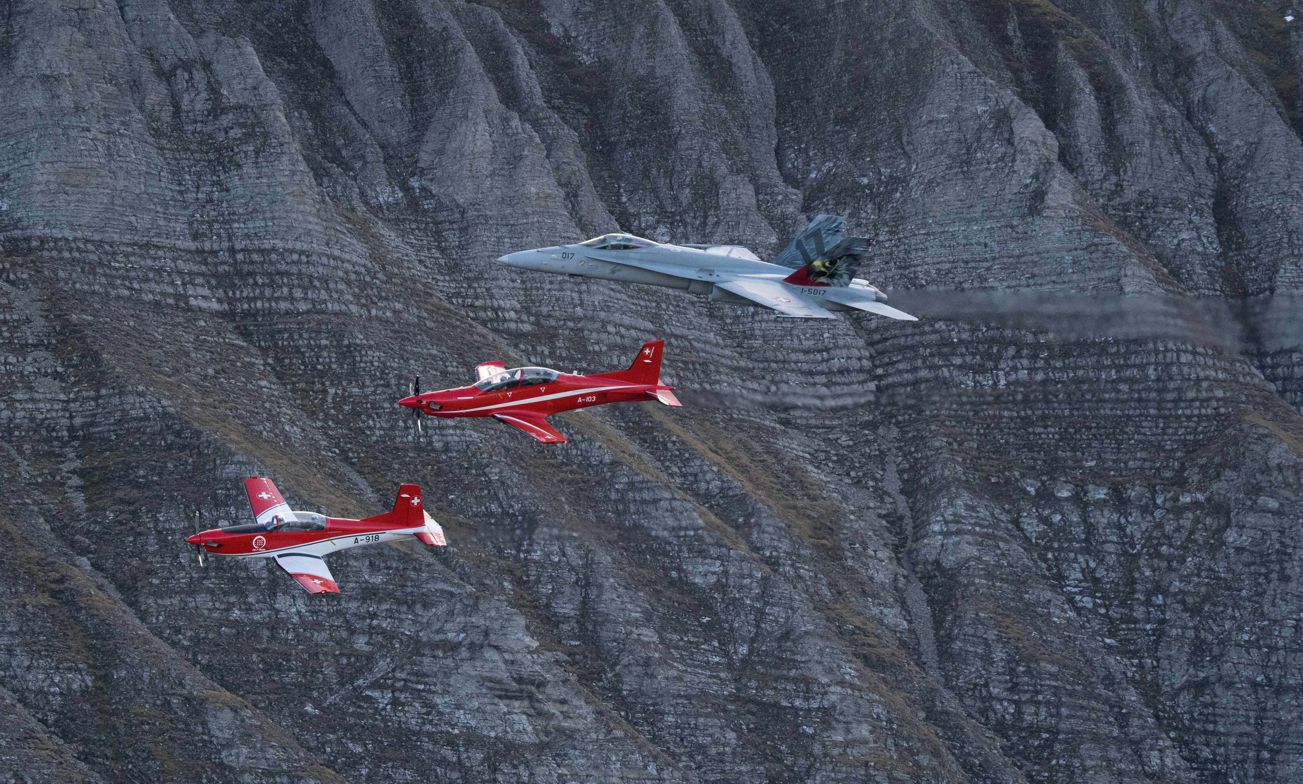 three red and white planes flying over a mountain, 
