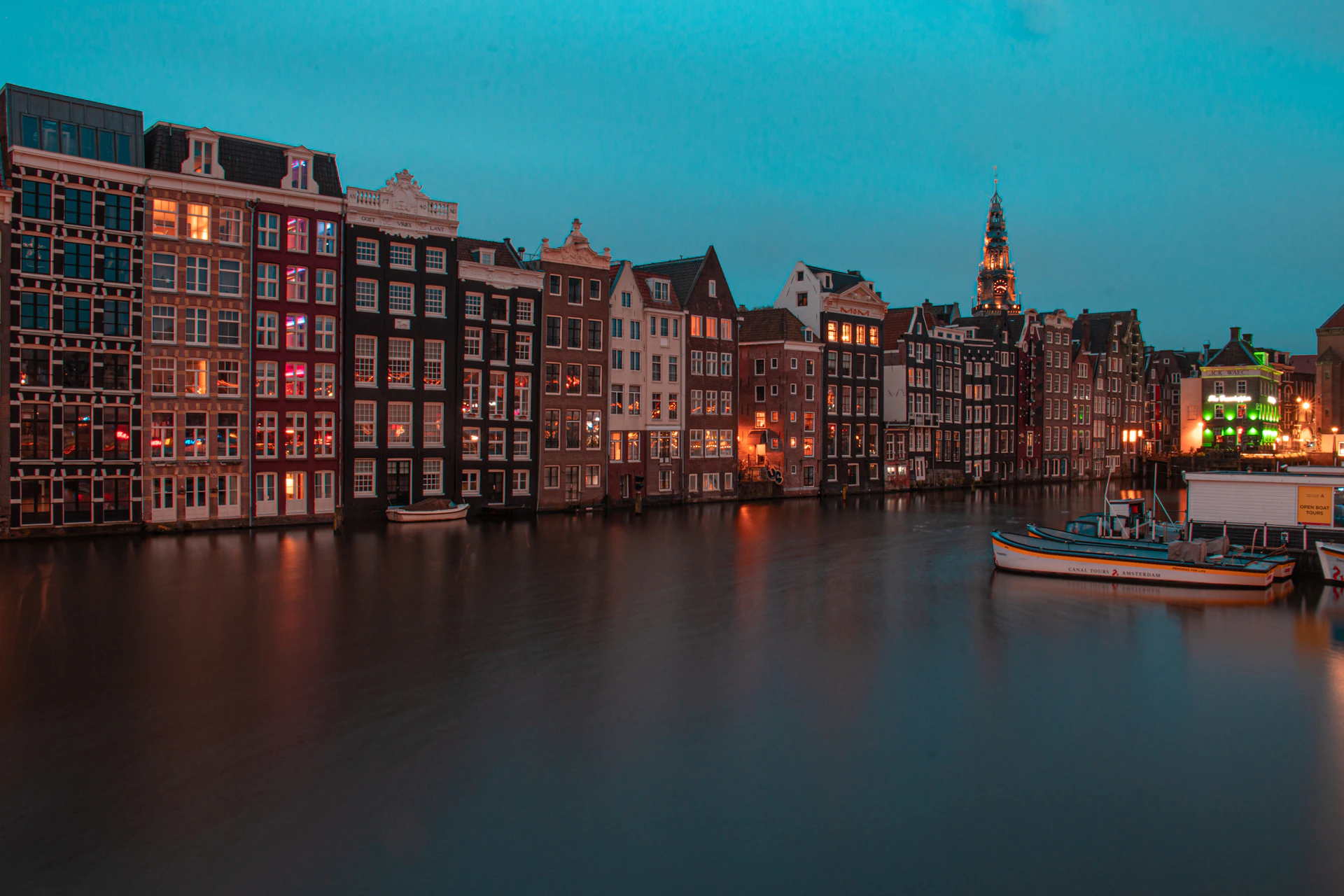 several boats are docked in a canal at night
