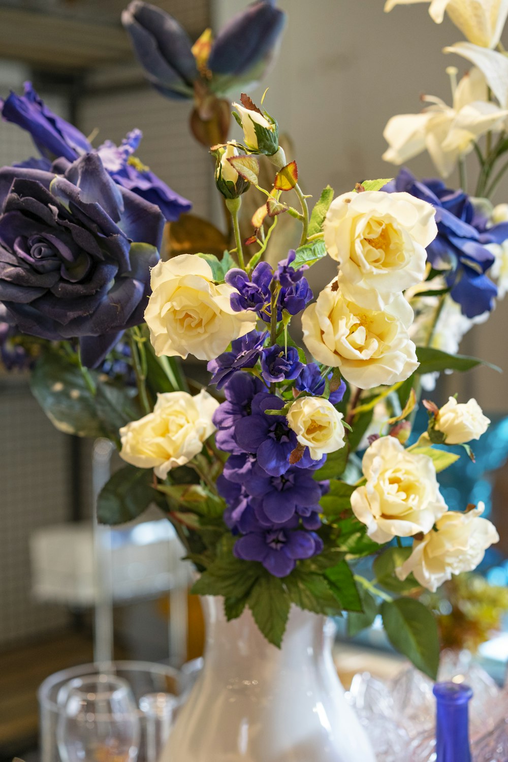 a white vase filled with blue and yellow flowers