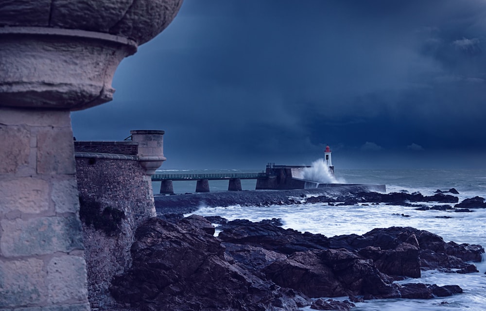 a lighthouse on a rocky shore under a stormy sky