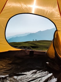 a yellow tent with a view of mountains