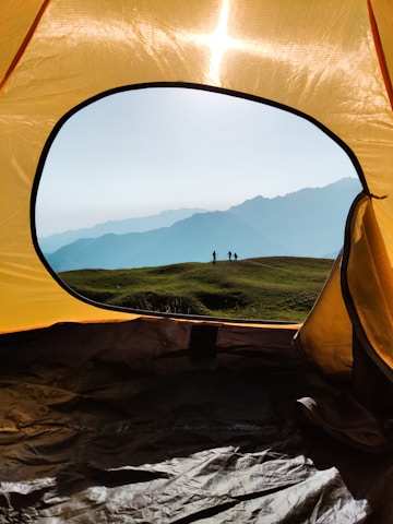 a yellow tent with a view of mountains