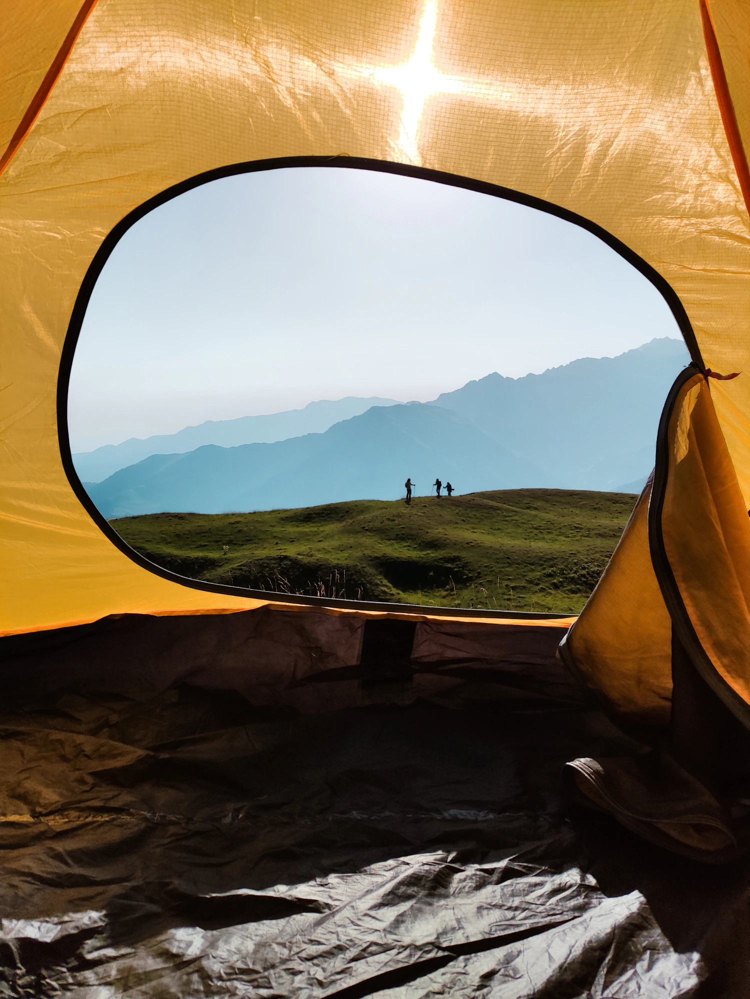 View of hikers and distant mountains from inside a camping tent