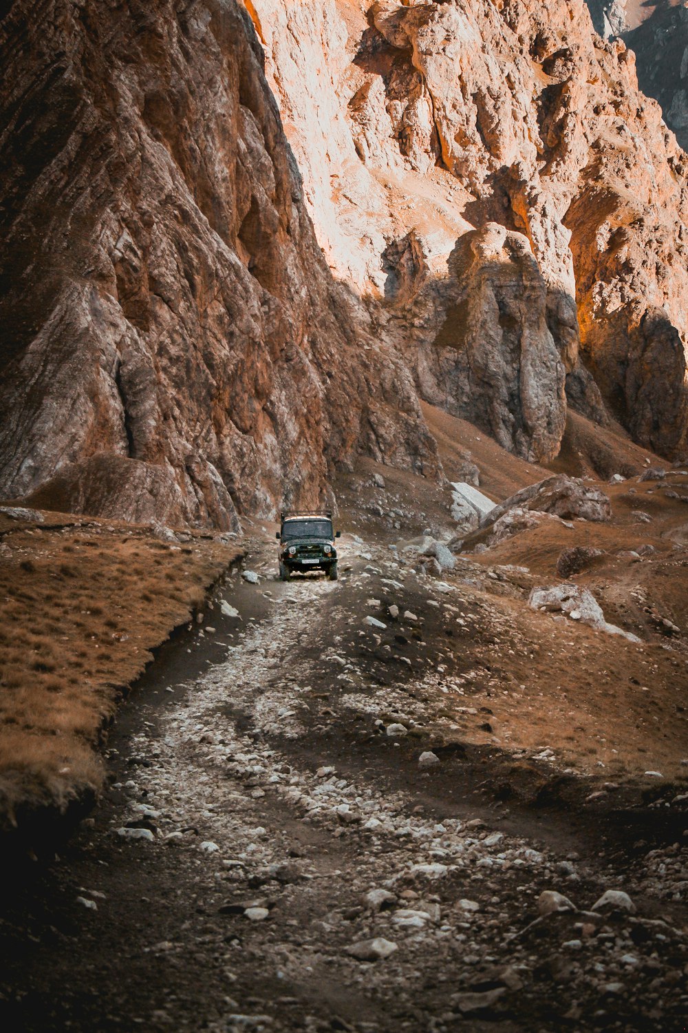 a car driving down a dirt road in the mountains