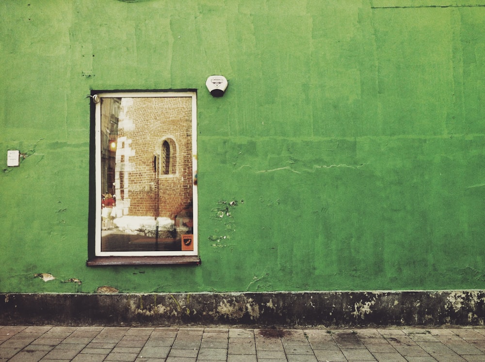 a green building with a window and a clock