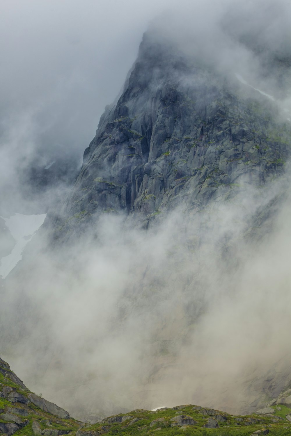 a mountain covered in fog and clouds on a cloudy day