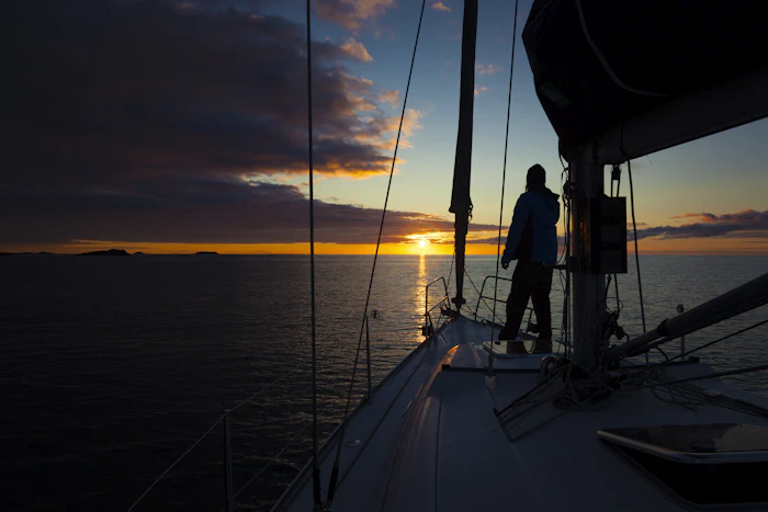 A guest standing on a boat deck watching the sun set over the water