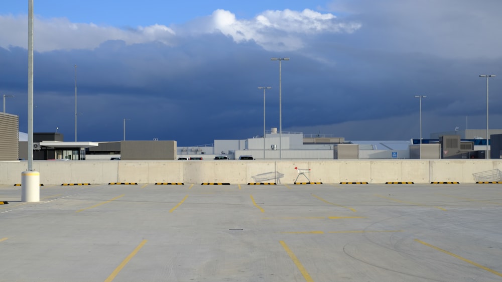 an empty parking lot with a cloudy sky in the background