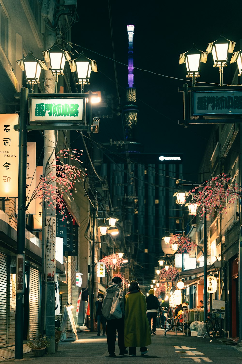 a couple of people walking down a street at night