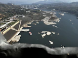 Aerial view of the Reschen Pass dam and lake with surrounding mountains.