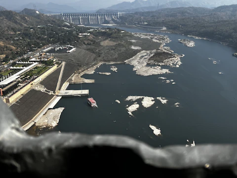 Aerial view of the Reschen Pass dam and lake with surrounding mountains.