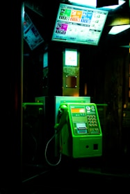 a green payphone sitting in a dark room