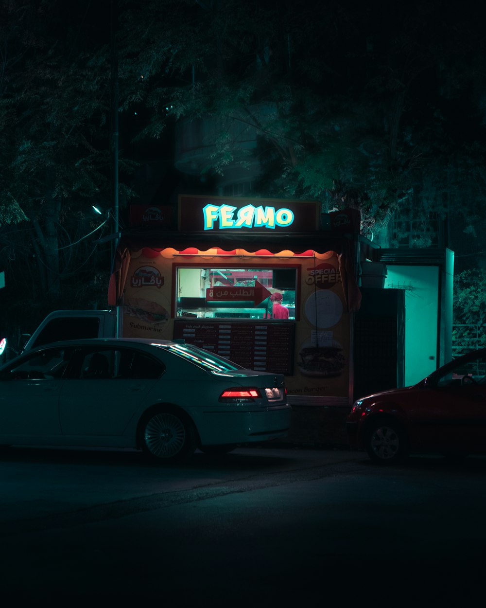 a car parked in front of a food stand at night