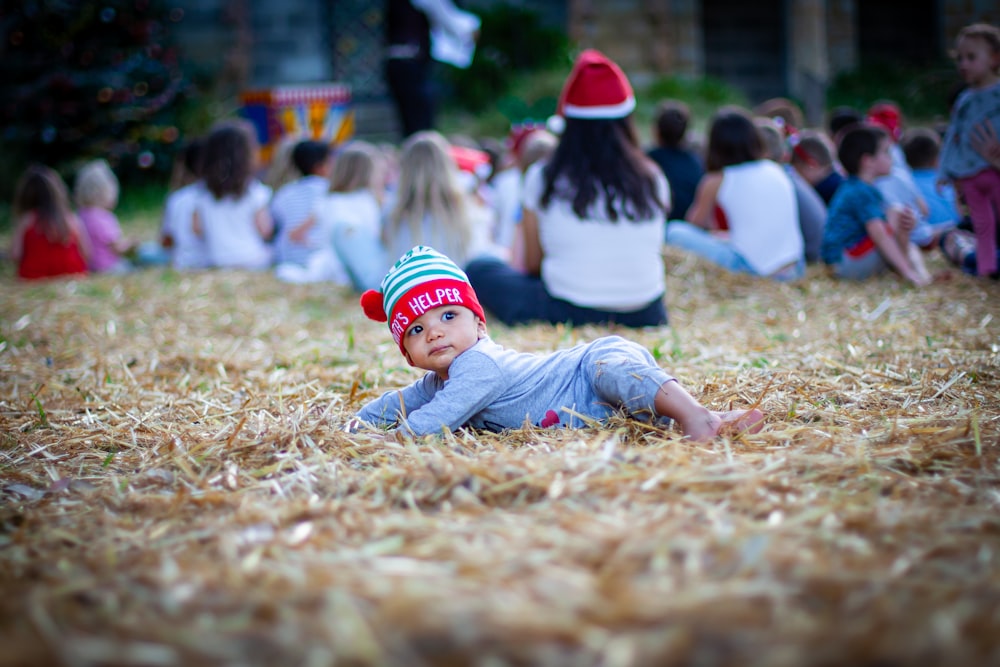 a baby laying on the ground wearing a santa hat