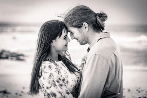 A warm, candid photo of a couple laughing together on a sun-drenched beach at golden hour.