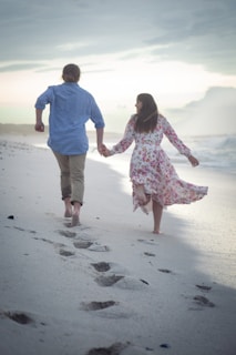 a man and a woman walking on a beach holding hands