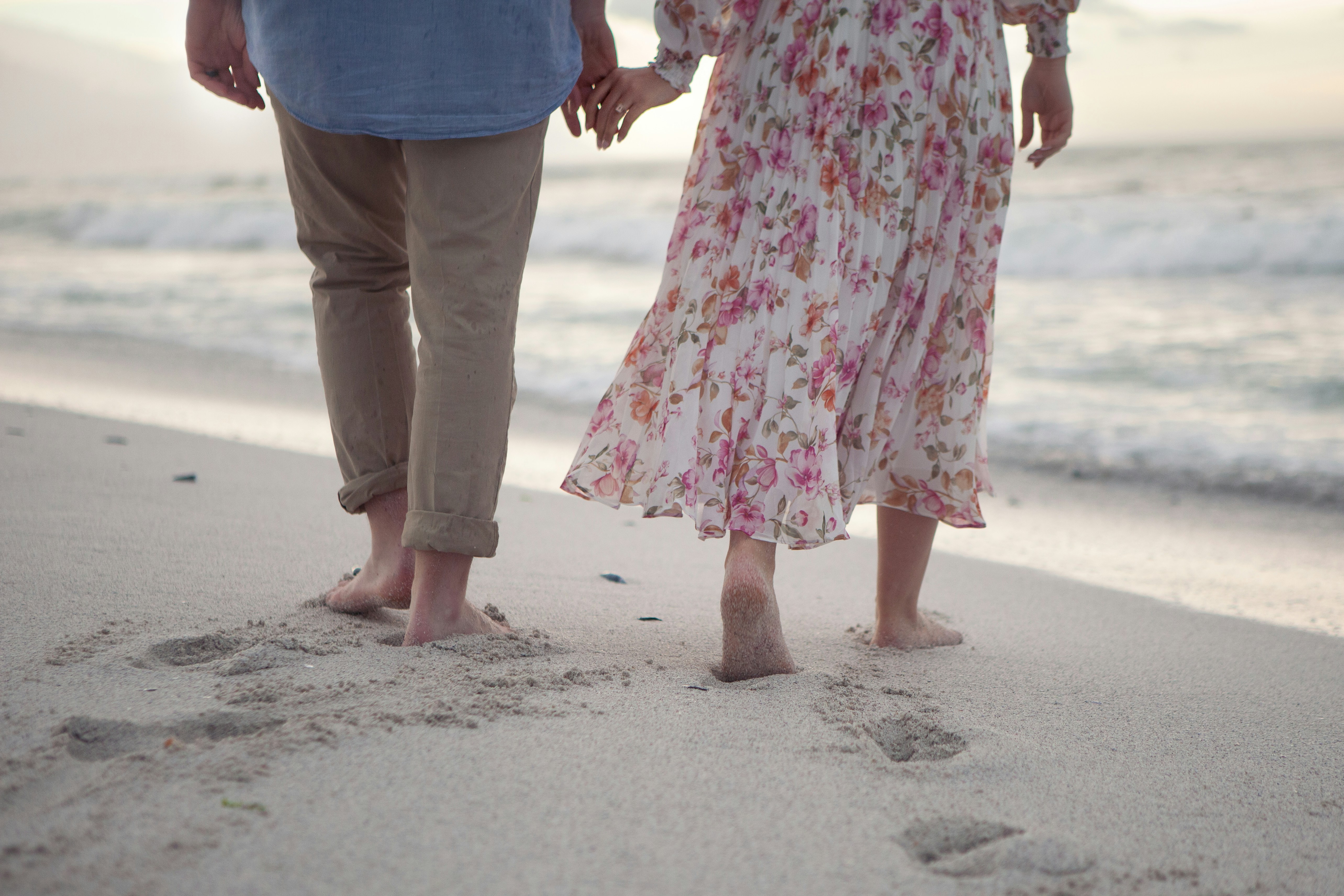 Couple holding hands walking on beach