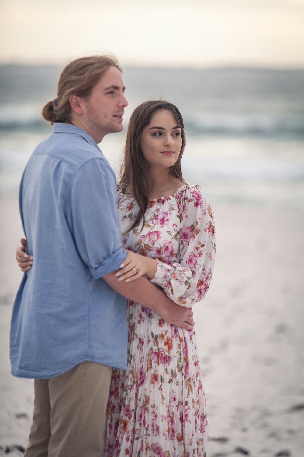 a man standing next to a woman on a beach