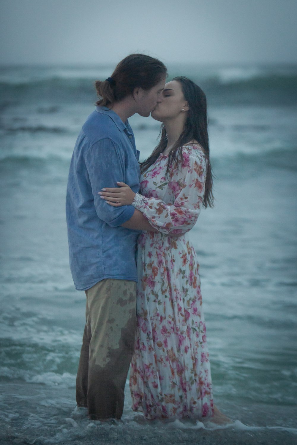 a man and a woman kissing in the ocean