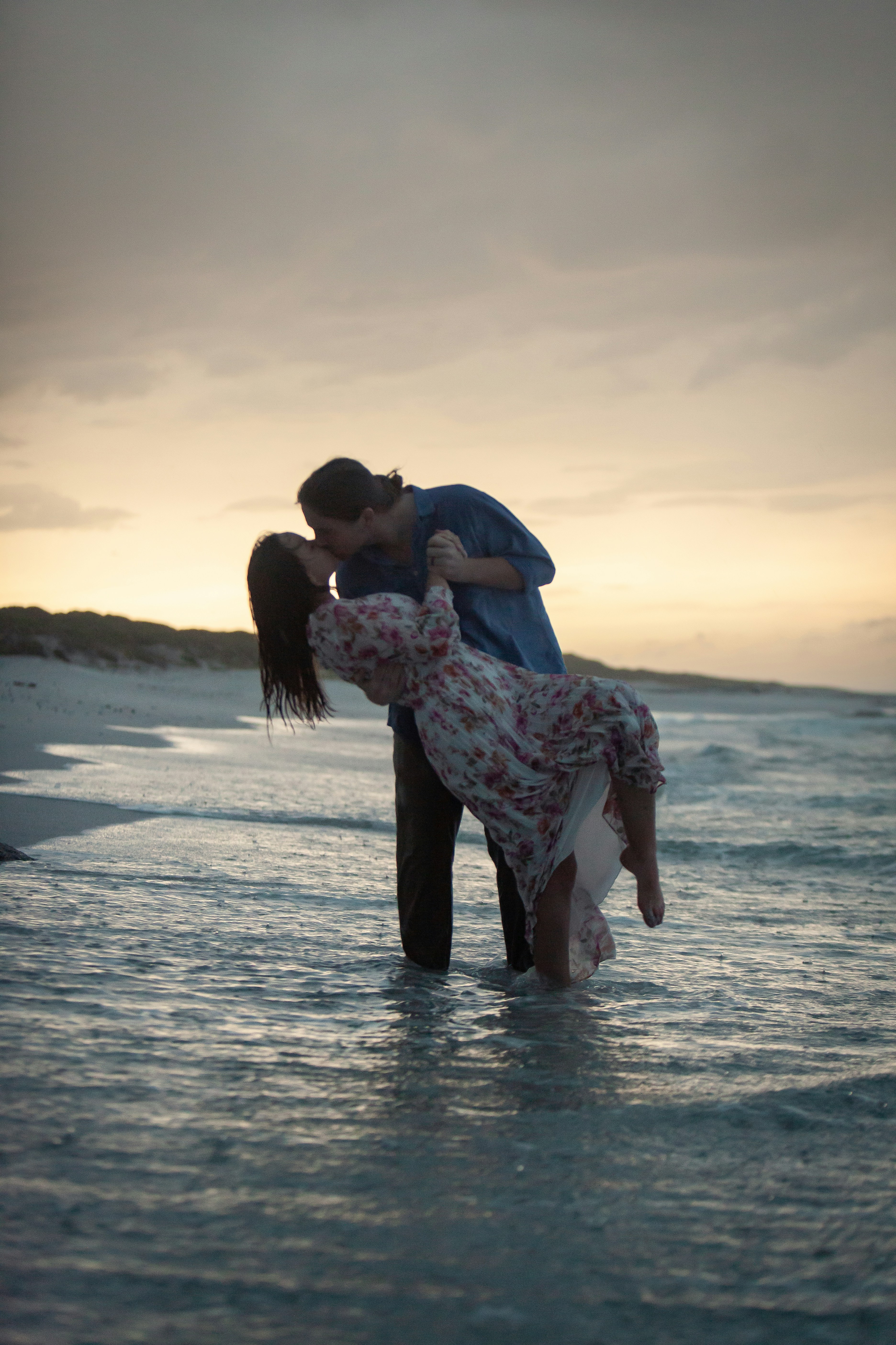a man and a woman kissing in the ocean