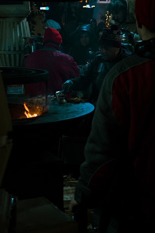 Smiling faces of tourists enjoying a traditional gaucho barbecue around a campfire at dusk.