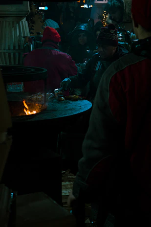 A group of friends happily gathered around a portable 14-inch gas grill enjoying a summer barbecue.