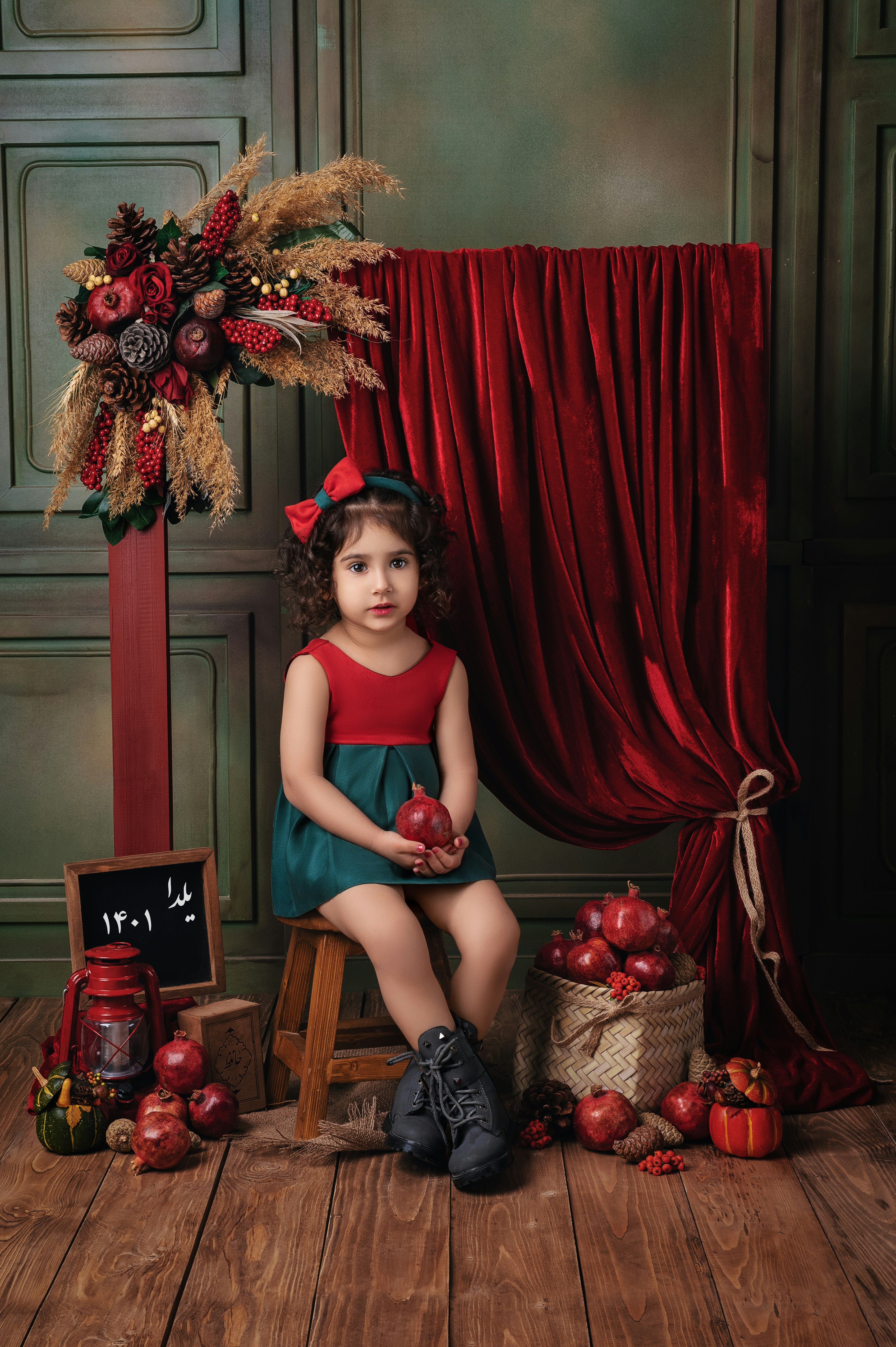 A little girl sitting on a stool with apples