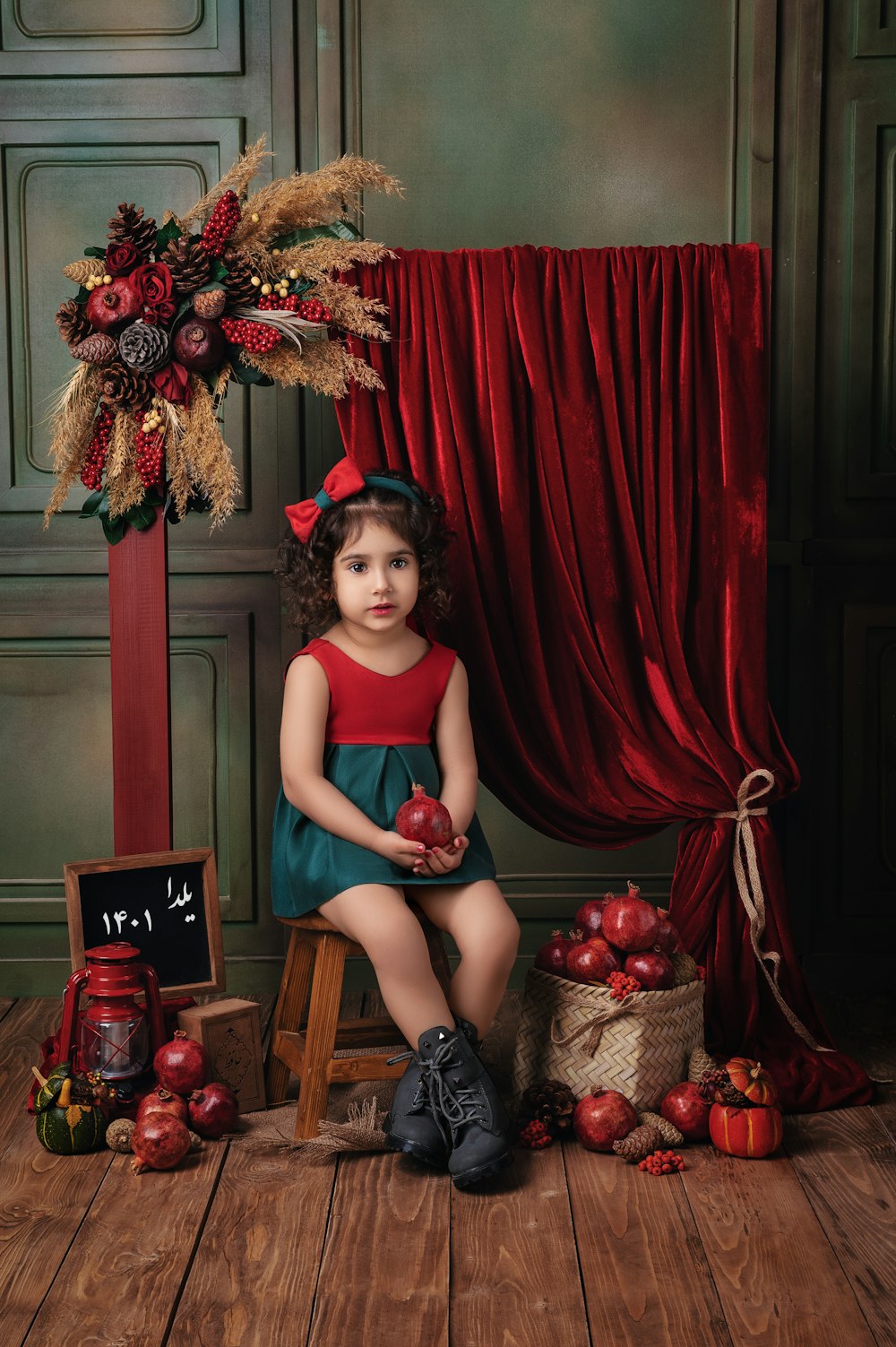 a little girl sitting on a stool with apples