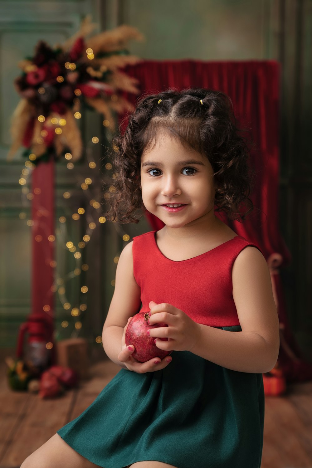 a little girl in a red dress holding an apple