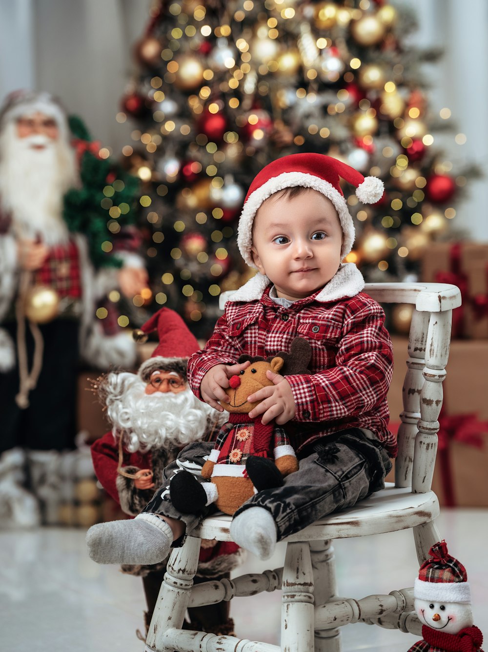 a baby sitting on a rocking chair with a christmas tree in the background