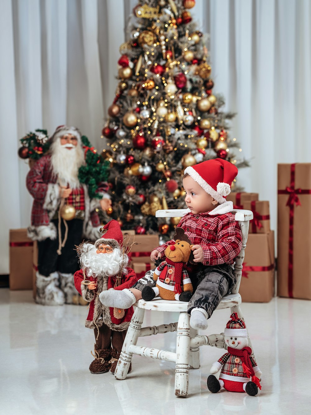 a small child sitting in a chair next to a christmas tree