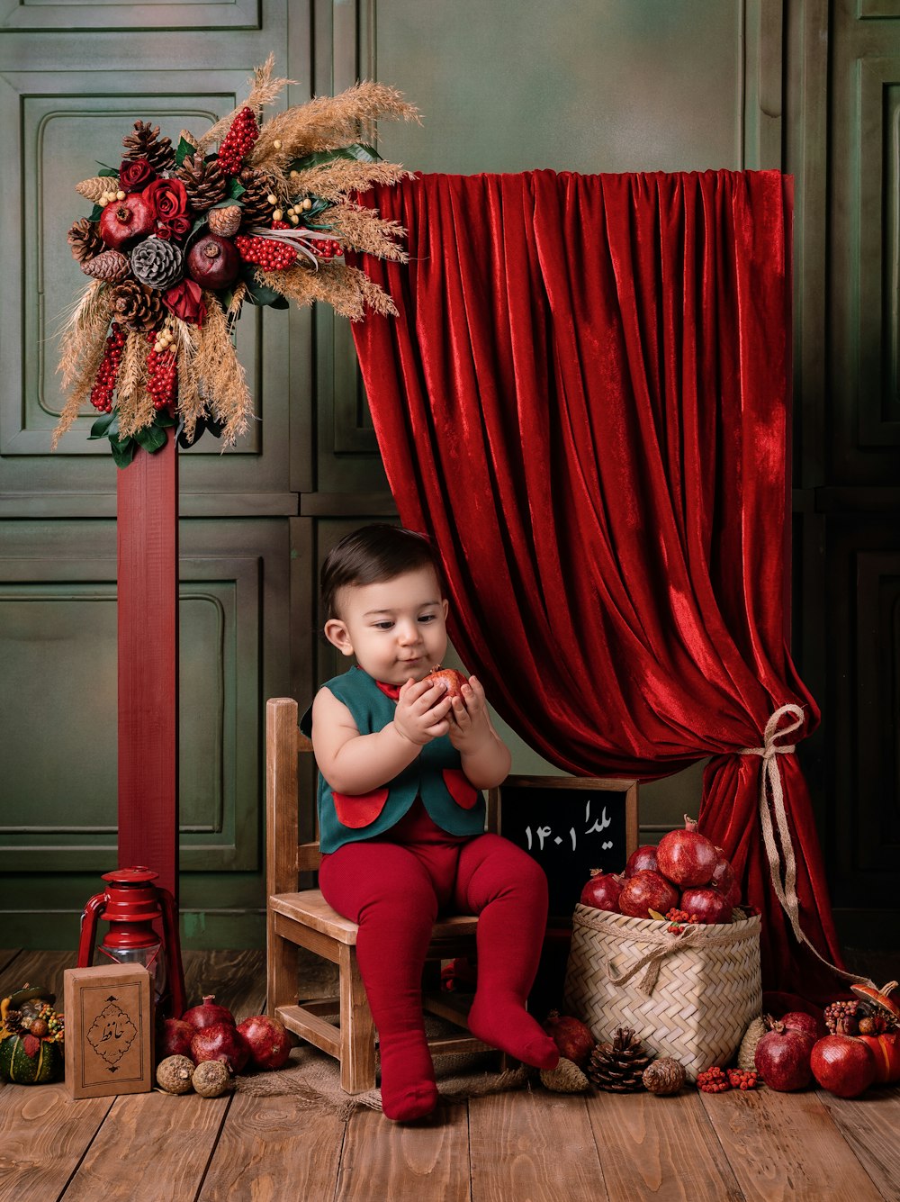 a little boy sitting on a chair in front of a red curtain