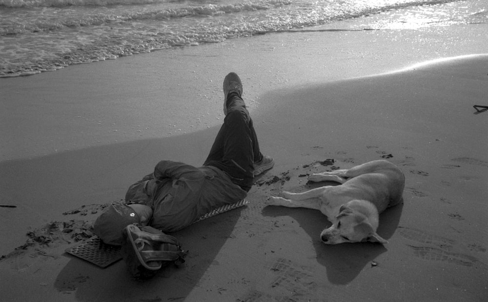 a person laying on the beach with a dog