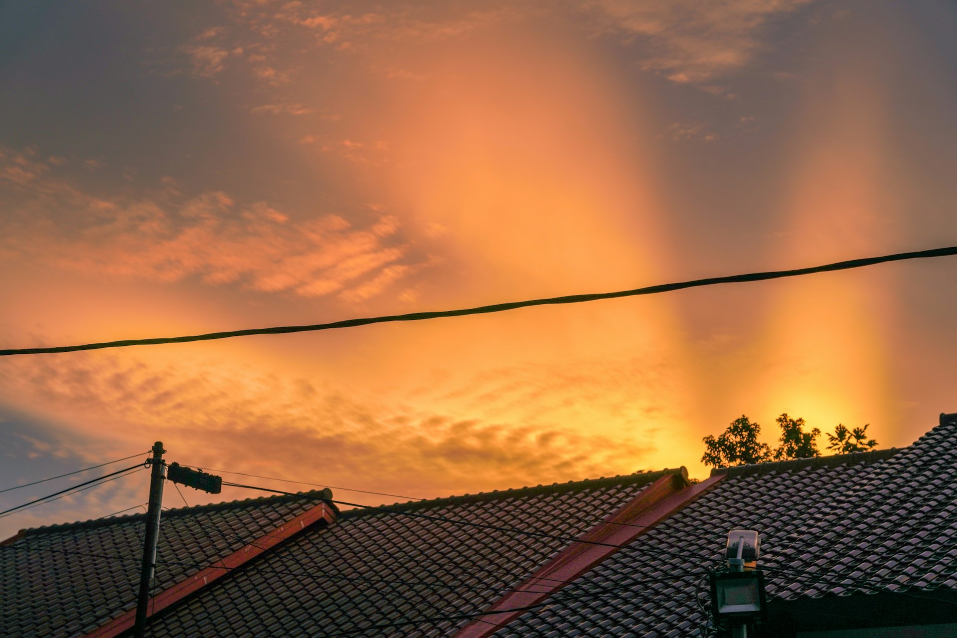 the sun is setting over the rooftops of a house