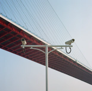 Close-up of CCTV cameras monitoring an industrial site under bright daylight.